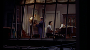 Rear Window (1954) - film frame - Film frame from ''Rear Window'' showing Hitchcock's cameo as a a clock winder in the musician's apartment.